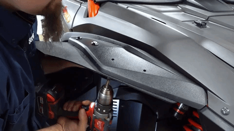 The person is drilling more holes and installing bolts into them.