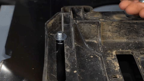 Using his fingers, a man tightens a nut onto a bolt.