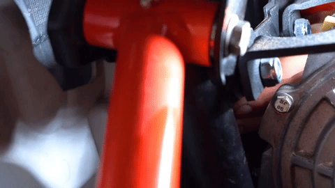 A close up of a hand turning a bolt inside the very tight quarters that is the inside of a UTV's front half.