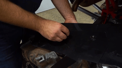 A hand tightens screws onto he same rectangular bracket from before.