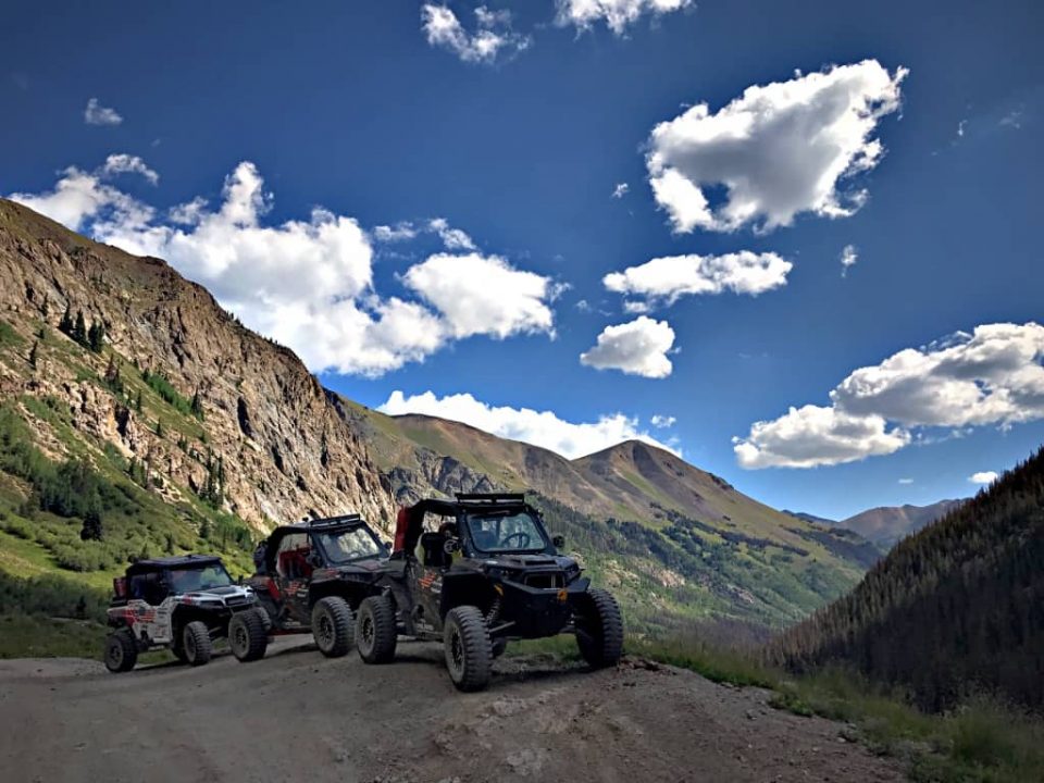 UTVs at mountain base with blue sky