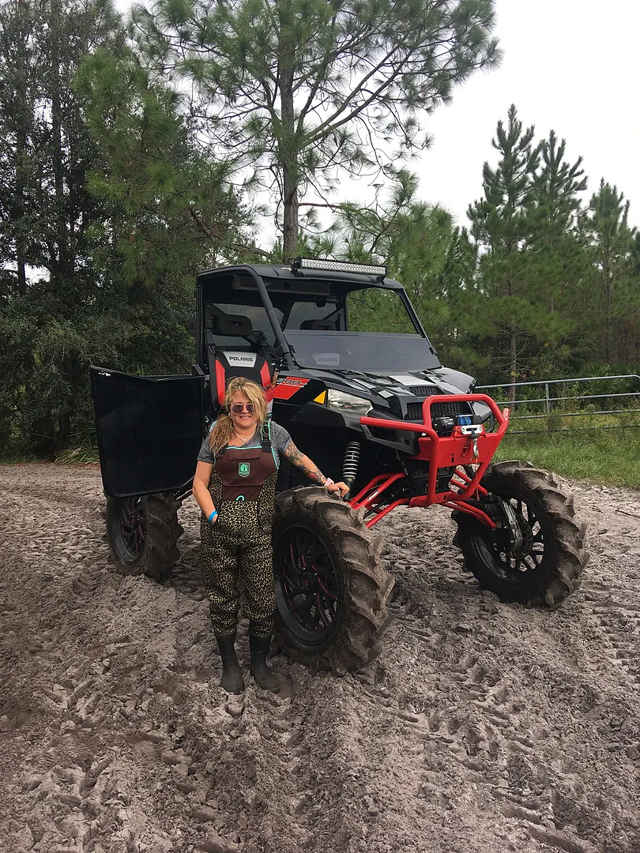 A Ranger XP 900 equipped with 8" GDP Portals in the dirt with a woman standing beside it in waders.