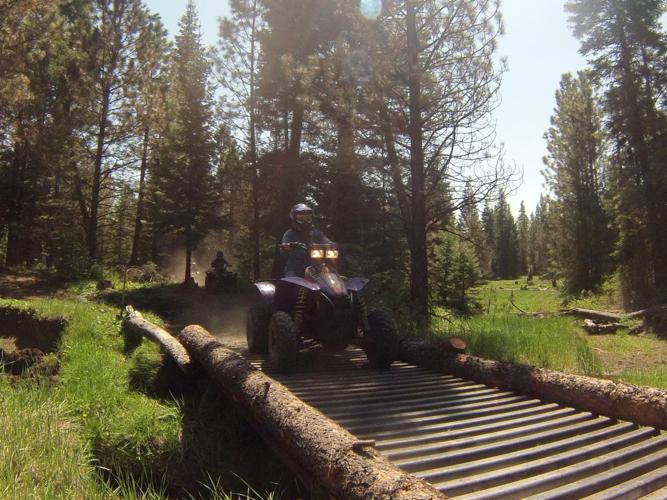 An ATV crossing a bridge on a trail