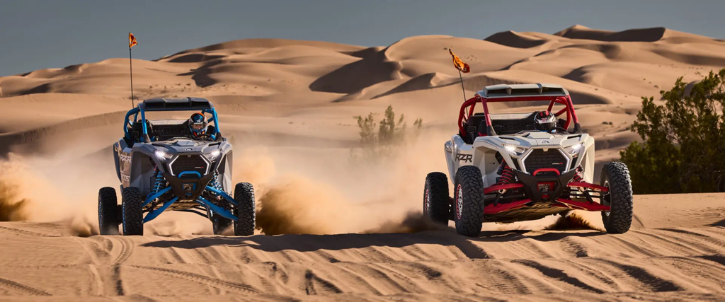 Two Polaris RZR Pro R machines driving over whoops in the desert