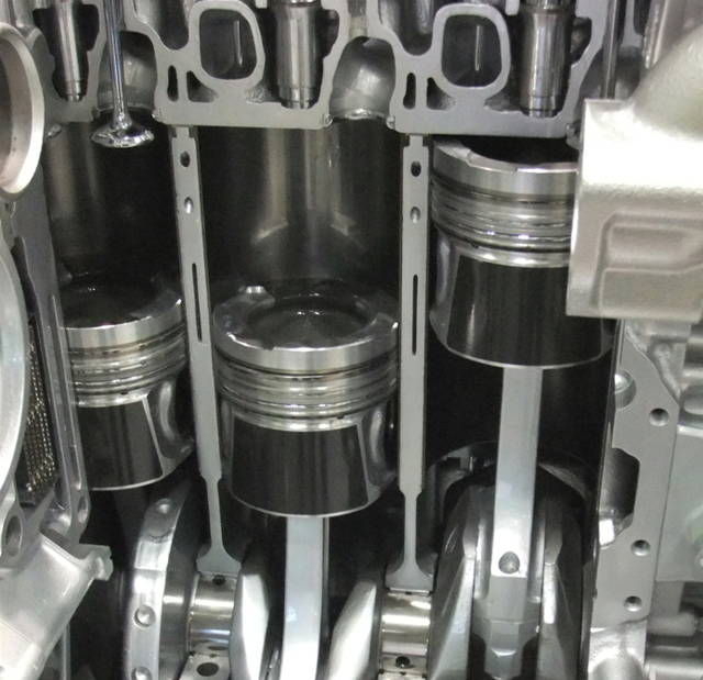 A photo of an engine that's cut away showing the pistons connected to the crankshaft.