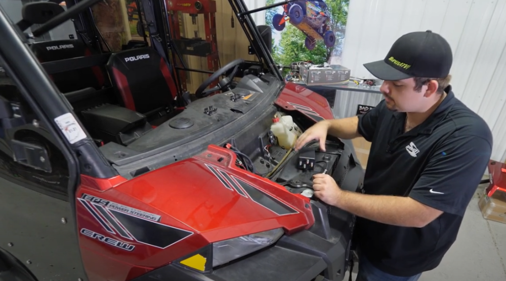 Braden moving parts around under the hood of the UTV.