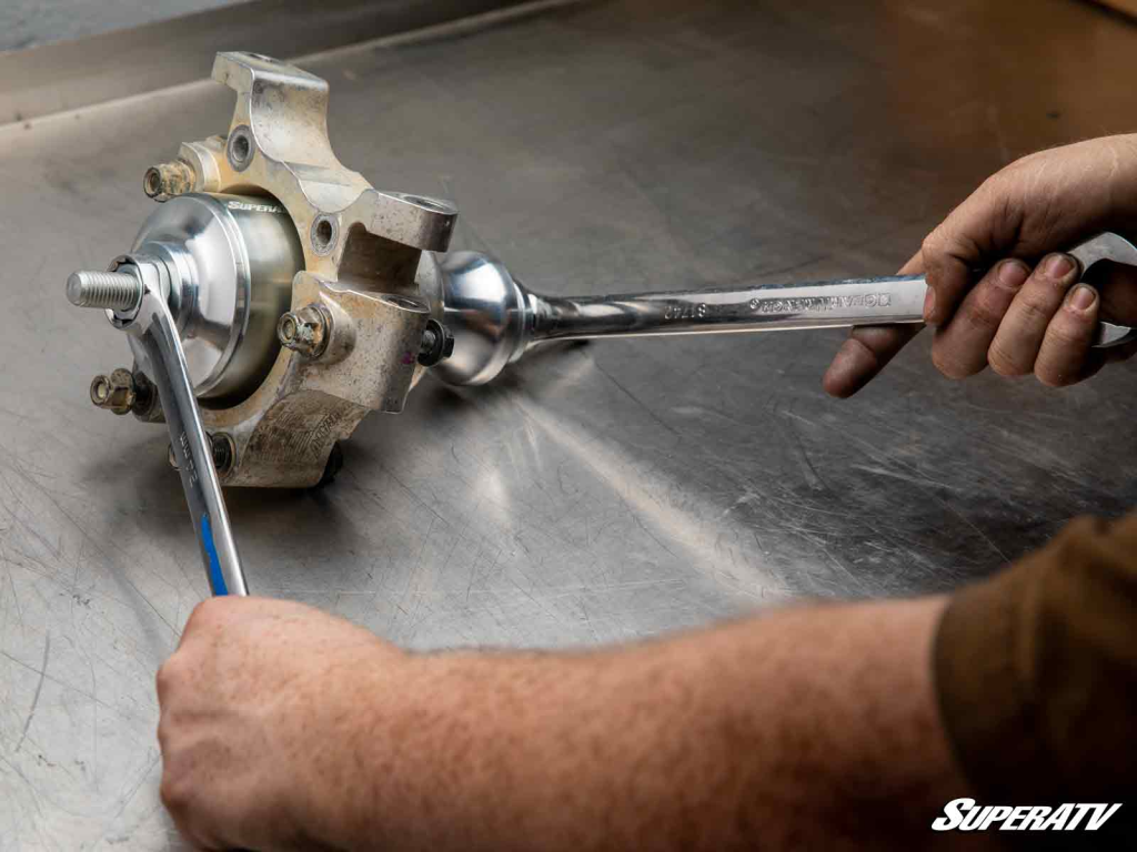 SuperATV's Polaris wheel bearing removal tool installed on a spindle and being torqued down with wrenches.