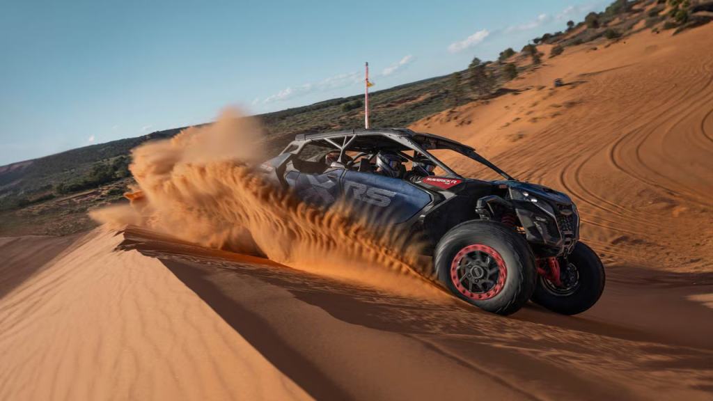 A Can-Am Maverick R racing across a sand dune.