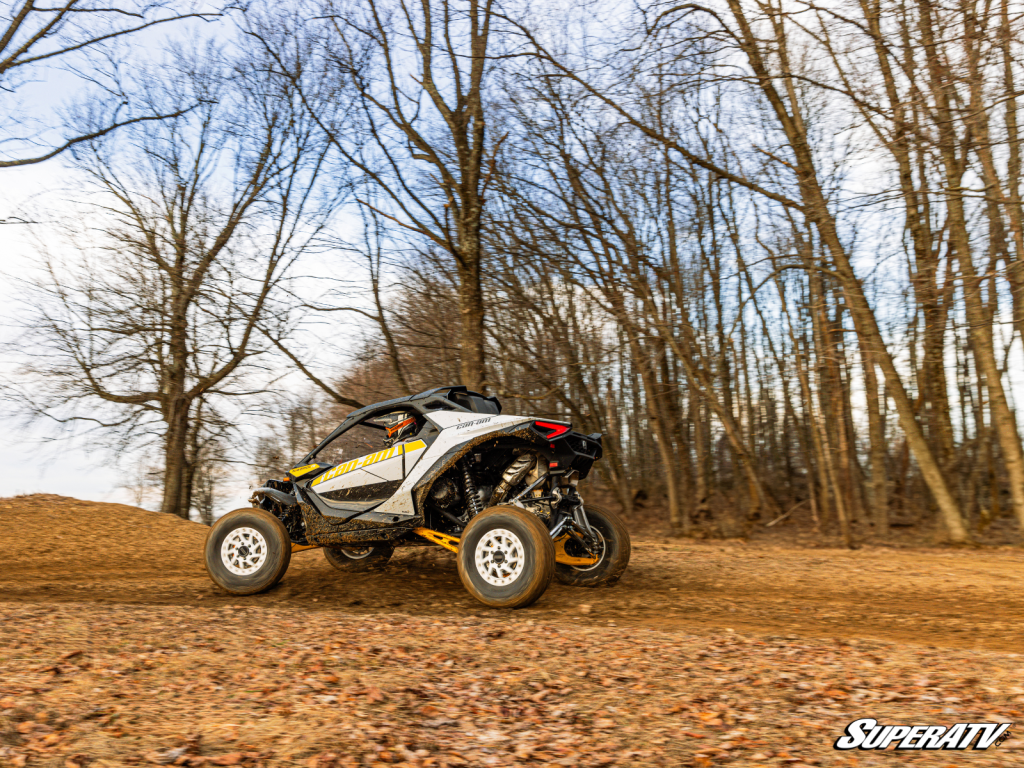 A Can-Am Maverick R ripping down a leaf-covered trail.