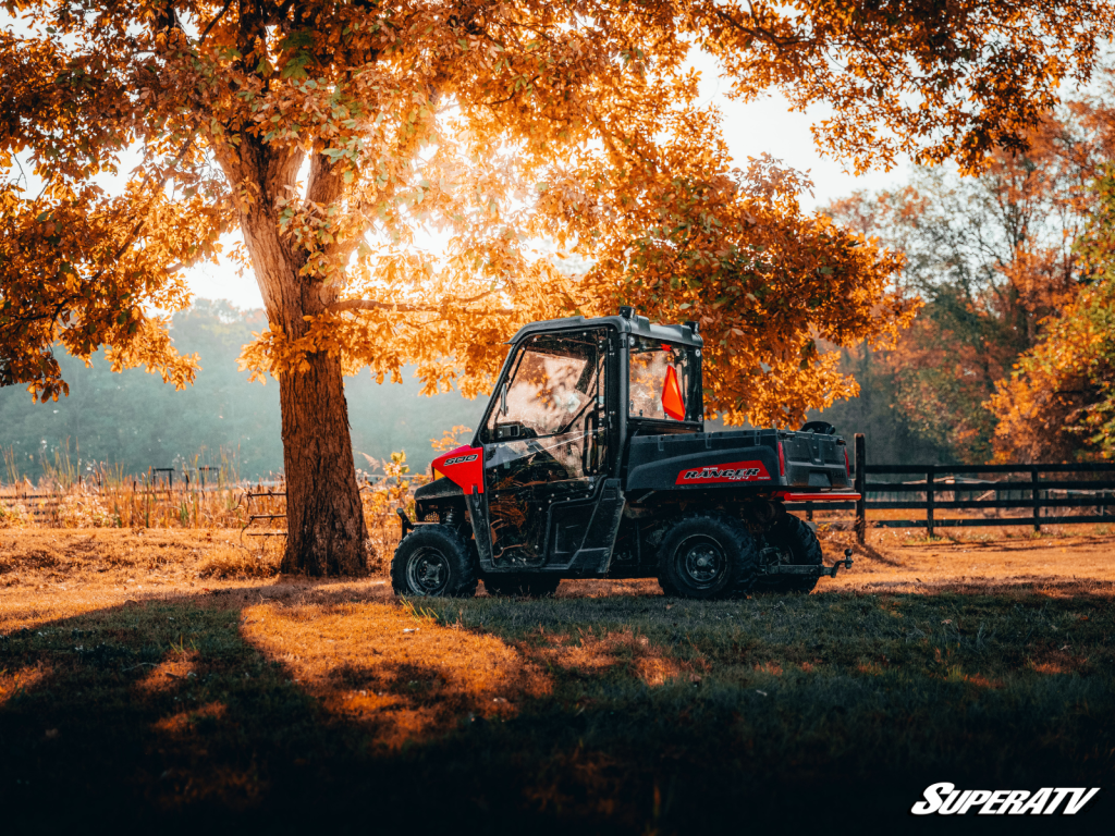 A Polaris Ranger parked in a farm-like setting under a big tree.