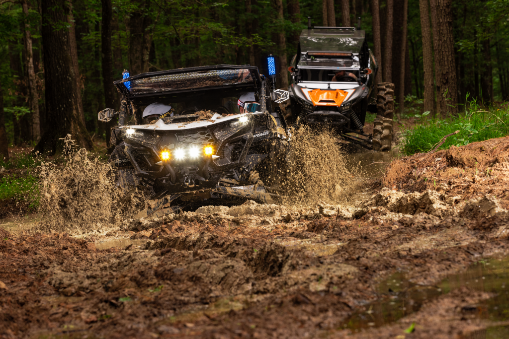 Two UTVs riding through mud with SuperATV's Magnum Whip Lights installed.