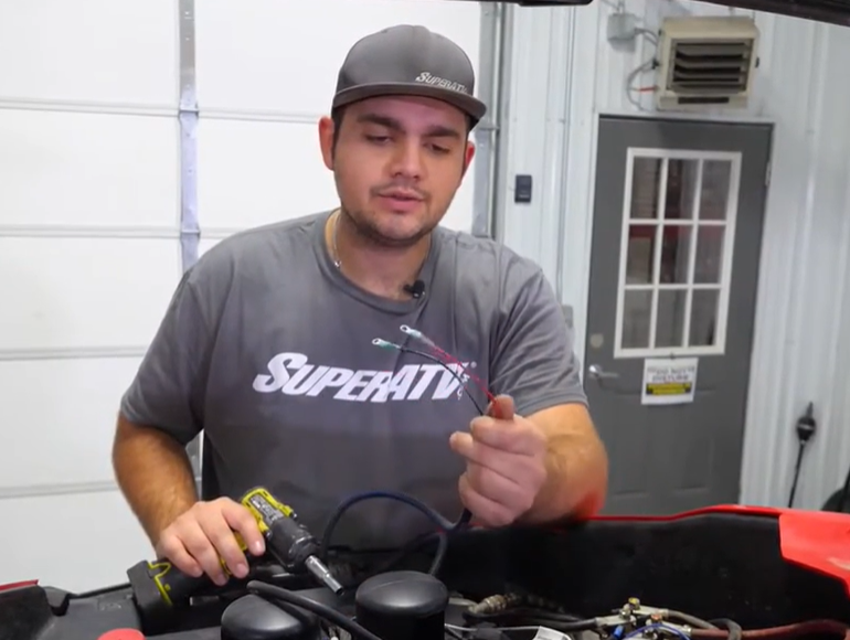 A mechanic wiring the UTV cab heater wires to a keyed on powersource.