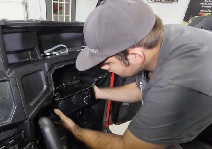 A mechanic mounting the heater inside the glove box. 
