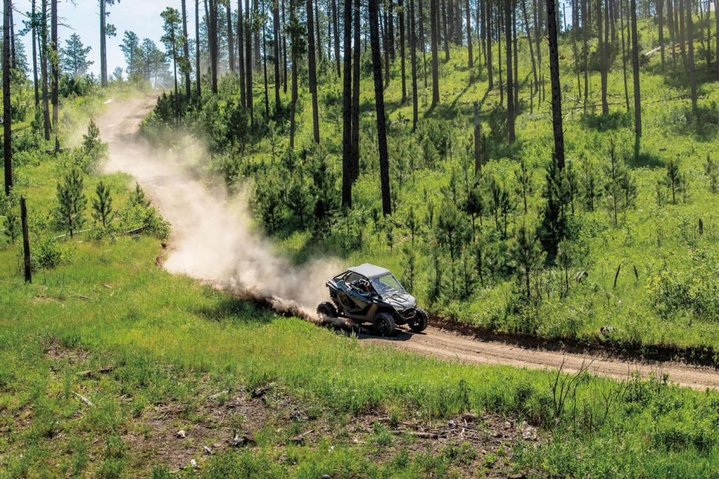 A Polaris RZR riding at high speed through a grassy mountainous clearing in West Virginia.