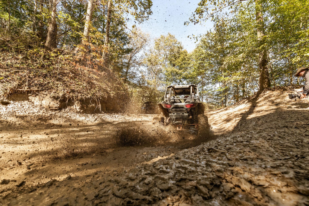 A Polaris RZR Riding through mud in the woods in West Virginia
