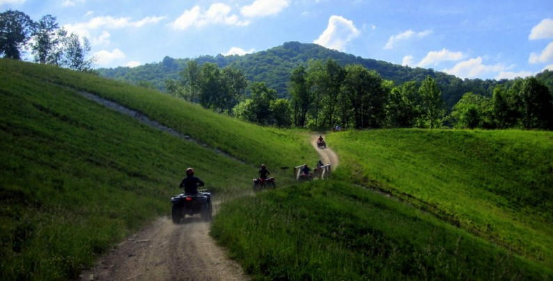 A convoy of ATVs riding on a grassy hillside in West Virginia