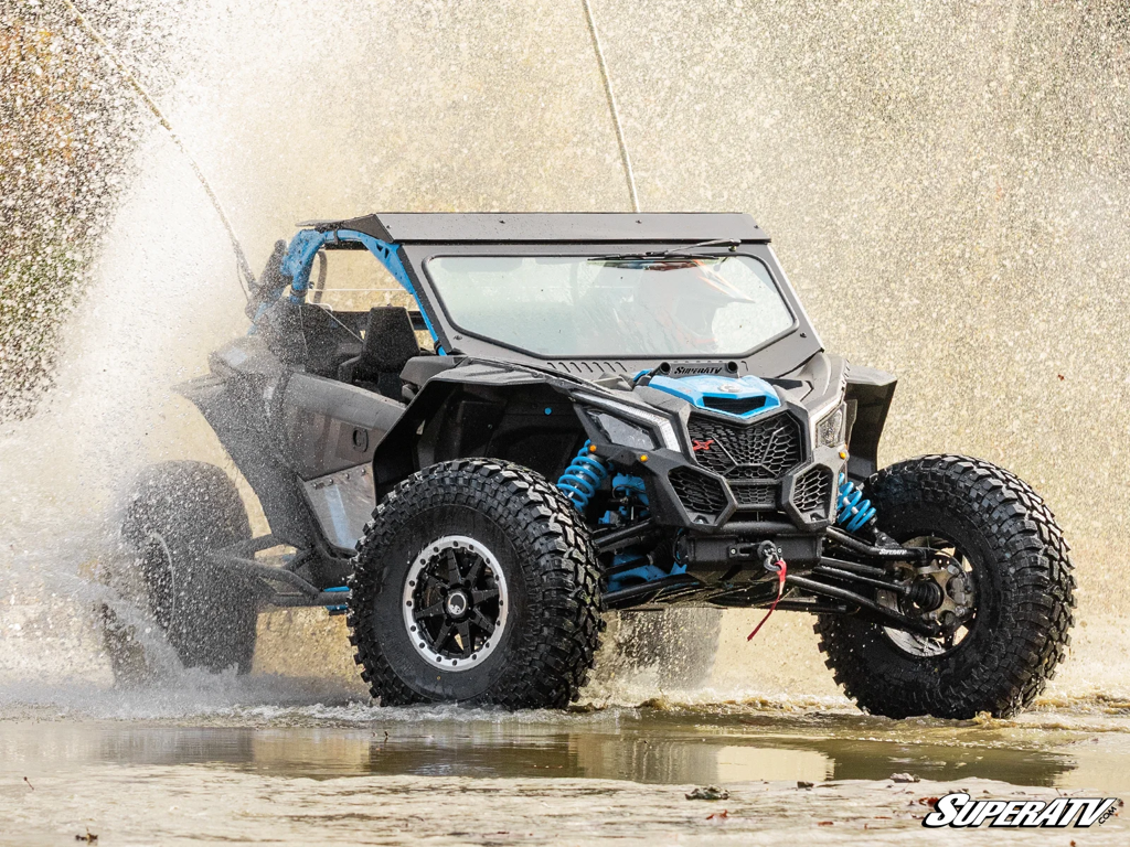 A MAverick X3 with SuperATV All-terrain tires riding in a creek