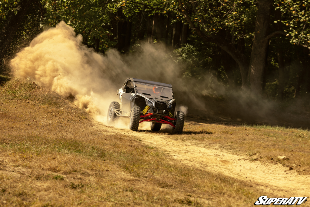 A Maverick X3 kicking up dirt while going around a corner on a track.