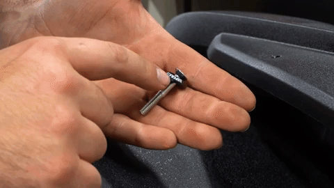 A hand inserts a bolt with a SuperATV-branded washer through the holes they just drilled.