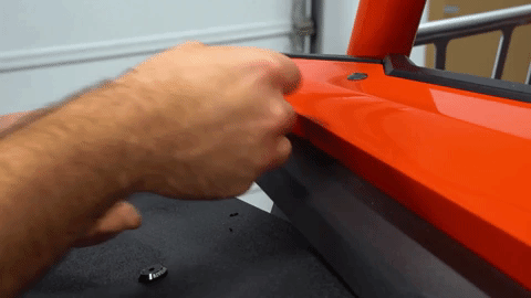A hand installs a bolt into a hole in the original fender.