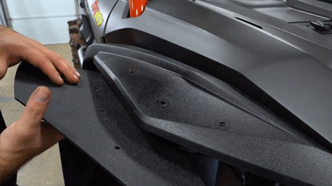 Two hands maneuver the fender flare under the OEM fender to align it.