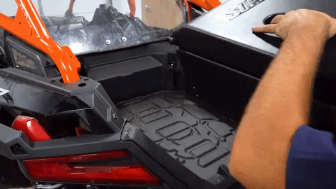 Brandon slides the cargo box into the bed area and begins to align it with the brackets.