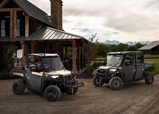 Polaris Rangers parked in front of cabin in mountains