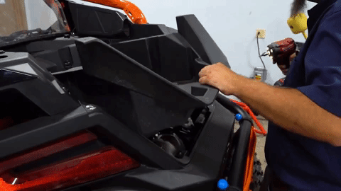 Brandon gently tugs on the plastic frame to wiggle it out of place to begin working on it.