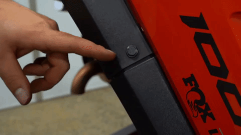 A person removes a round plastic push pin from the OEM fender with a small tool.