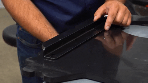 A man uses a table to hold two bolts in place before he installs the nuts to hold them in place.