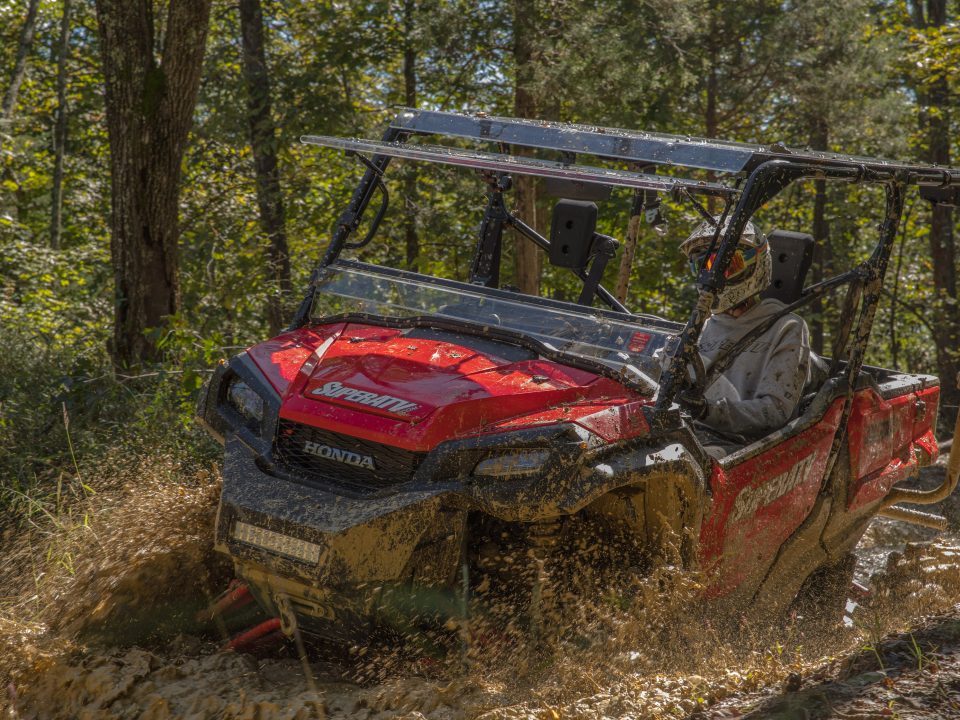 A Honda Pioneer 1000 going fast through some mud