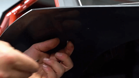 The hand tightens a nut to the under side of the bolt they just placed through the OEM fender and the fender flare.