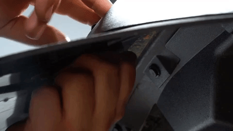 Two hands work together to tighten a nut onto a bolt going through a fender flare.